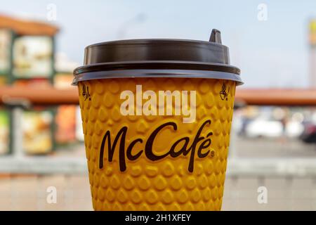 Verre jaune en papier avec du café pour les boissons McCafe sur la table contre la ville floue de McDonald's.Expérience dans le domaine de la restauration rapide.Restauration rapide Banque D'Images