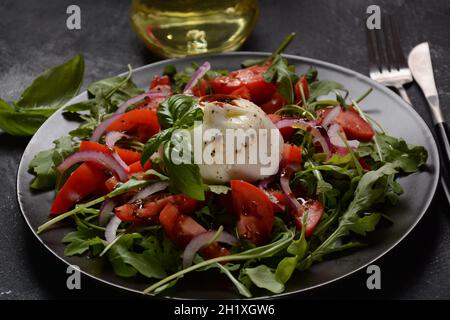 Salade avec tomates et fromage Burrata avec basilic et huile d'olive sur fond sombre. Fromage burrata traditionnel italien. Burrata servi avec tomat Banque D'Images