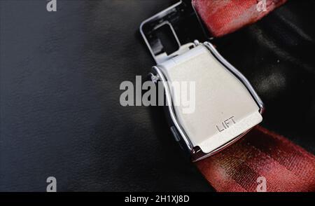 Ceinture sous-abdominale rouge d'un siège vide à l'intérieur d'un avion avec le mot « LIFT » en relief sur le métal.Voyage en toute sécurité Banque D'Images