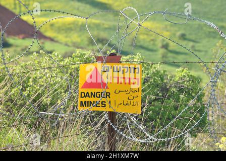 Le champ de mines danger mine un panneau d'avertissement jaune sur une clôture barbelée sur les hauteurs du Golan, Israël Banque D'Images