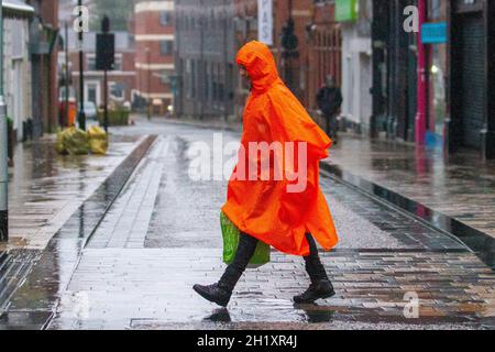 Homme portant un imperméable en plastique orange pleine longueur à Preston, Lancashire.Royaume-Uni 19 octobre 2021.Boutiques, shopping lors d'une journée humide dans le centre-ville de Preston.Credit:MediaWorldImages/AlamyLiveNews Banque D'Images