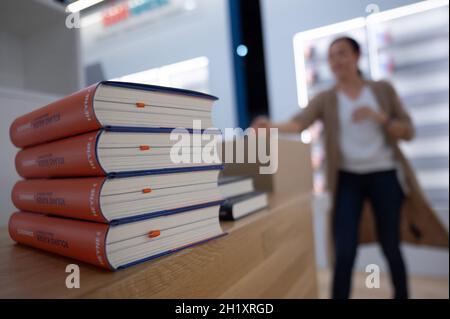 Hessen, Francfort-sur-le-main: 19 octobre 2021, 19 octobre 2021, Hessen, Francfort-sur-le-main: Une femme dépose des livres au stand du Penguin Random House Publishing Group lors de la mise en place de la Foire du livre de Francfort 2021.La cérémonie d'ouverture de la foire, qui s'étend du 20 au 24 octobre, a lieu le soir du 19 octobre.Photo: Sebastian Gollnow/dpa Banque D'Images