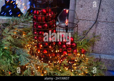 Décorations de Noël affichées à l'extérieur par fenêtre. Branches de sapin enneigé de Noël élégantes avec boules festives sur un rebord de fenêtre dans la rue d'un festif Banque D'Images