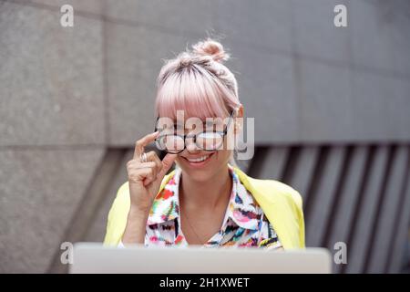 Dame gaie abaissant des lunettes des yeux et regardant à l'appareil photo Banque D'Images