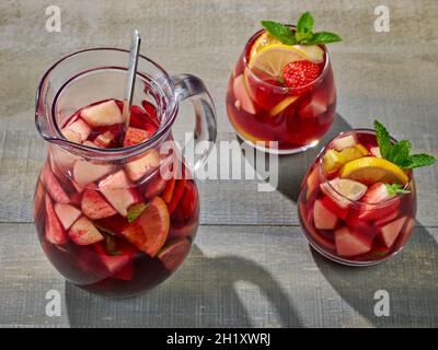 carafe et verres de sangria rouge sur une table de cuisine en bois Banque D'Images