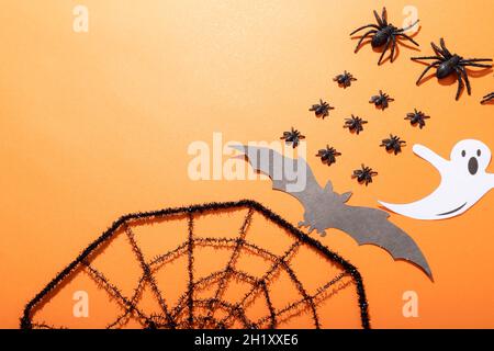 Composition de décorations d'halloween avec rangées d'araignées noires, toile d'araignée et fantôme sur orange Banque D'Images