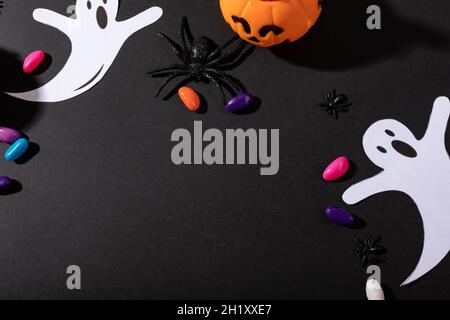 Composition de décorations d'halloween avec araignée noire, fantômes et citrouille sur fond noir Banque D'Images