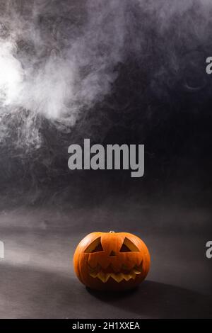 Composition de la citrouille sculptée d'halloween et nuage de fumée avec espace de copie sur fond noir Banque D'Images