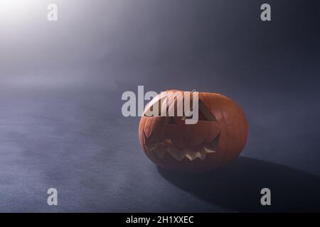 Composition de la citrouille sculptée d'halloween et nuage de fumée avec espace de copie sur fond noir Banque D'Images