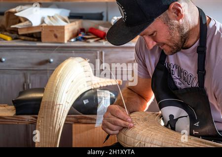 L'ancien champion du monde Patxi Tambourindeguy réparse un grand chistera dans son atelier de pelota à Bidart, France Banque D'Images