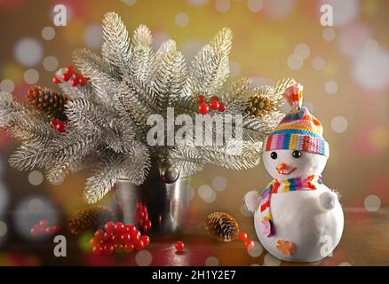 Bonhomme de neige sur fond de branches de sapin avec guirlande de Noël.Carte de Noël. Banque D'Images