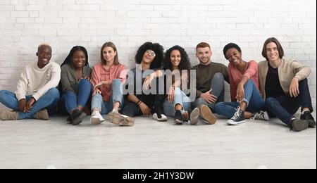 Des étudiants multiraciaux insouciants qui se rafraîchissait ensemble sur le sol Banque D'Images