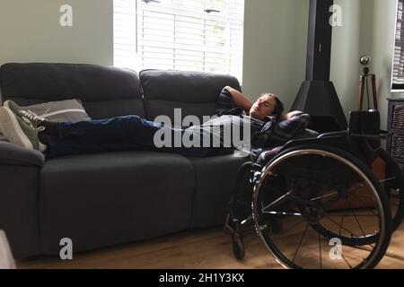 Homme casien handicapé prenant une sieste sur le canapé à la maison Banque D'Images