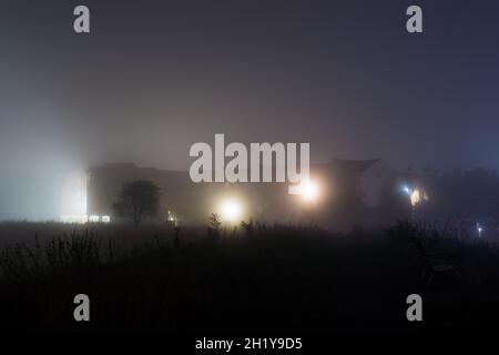 Un montage atmosphérique de bâtiments à la périphérie de la ville, rétro-éclairé sur une nuit brumeuse .UK Banque D'Images