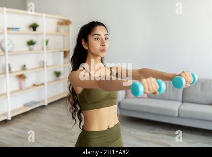 Sports domestiques pendant le maintien du covid.Femme indienne forte faisant des exercices avec des poids, s'exerçant avec des haltères Banque D'Images