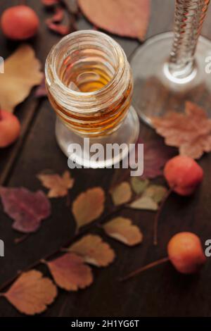 Un verre de vin dessert avec des feuilles d'automne et des baies sur une table en bois Banque D'Images