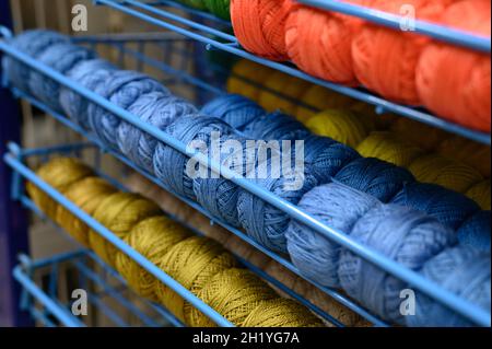 rangées de boules de fils de coton colorés pour tricoter les couleurs bleu, rouge et moutarde sur les tablettes du magasin Banque D'Images