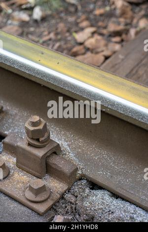 Gros plan de l'usure latérale accrue des rails en acier avec des copeaux métalliques dans une courbe très raide. Banque D'Images