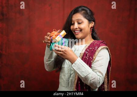 Portrait de femme indienne excitée par l'ouverture boîte cadeau surprise - concept showinf d'anniversaire, anniversaire Valentin ou cadeaux inattendus Banque D'Images