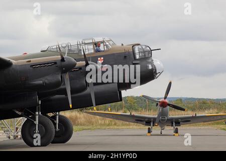 Bataille de Grande-Bretagne, vol commémoratif Lancaster Bomber contrôle les moteurs à l'aérodrome de Duxford, Cambridgeshire, avec un Spitfire en arrière-plan Banque D'Images