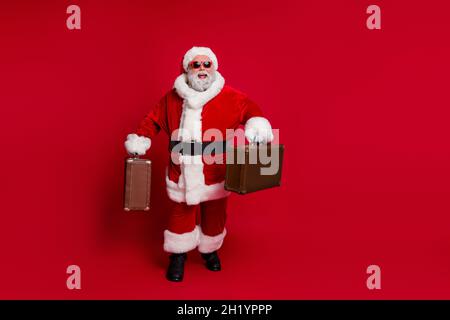 Photo de drôle excitée santa claus porter chapeau de tête rouge lunettes sombres sourire hurlier vérifier dans isolé rouge couleur fond Banque D'Images