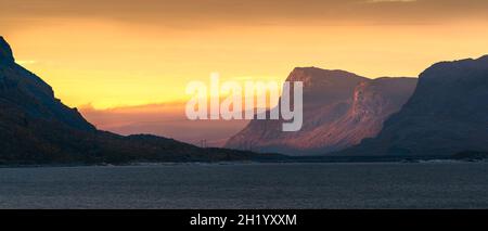 Le soleil se lève dans le brouillard, ce qui rend le ciel jaune, et illumine les sommets spectaculaires des montagnes dans le paysage arctique lointain du parc national Stora Sjofallet, en Laponie Banque D'Images