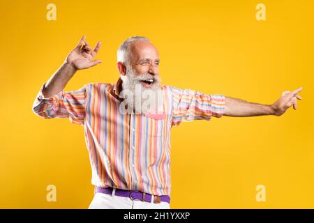 Portrait d'un sympathique cool funky gai gris-cheveux homme ayant le plaisir de se déplacer isolé sur fond jaune vif de couleur Banque D'Images