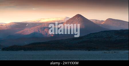 Le soleil se lève dans le brouillard, ce qui rend le ciel jaune, et illumine les sommets spectaculaires des montagnes dans le paysage arctique lointain du parc national Stora Sjofallet, en Laponie Banque D'Images