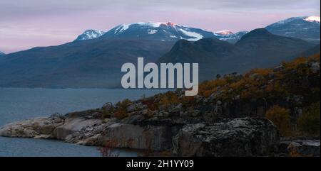 Les premiers rayons rouges de la lumière du matin éclairent les sommets des montagnes dans la nature sauvage de l'arctique.Parc national Stora Sjofallet, Suède.Lever du soleil sur la montagne Banque D'Images