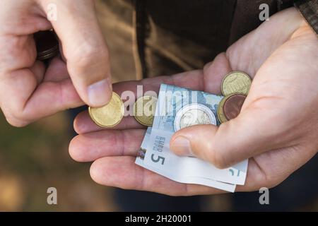 Un homme comptant des centimes d'euro et de petits billets dans la paume de sa main, gros plan Banque D'Images