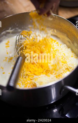Un cuisinier prépare une sauce au fromage pour faire du fromage macaroni Banque D'Images
