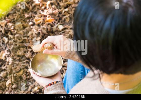 Femme jouant sur un bol de chant tibétain pour la thérapie sonore dans l'atmosphère pour la guérison, la méditation et la détente. Banque D'Images