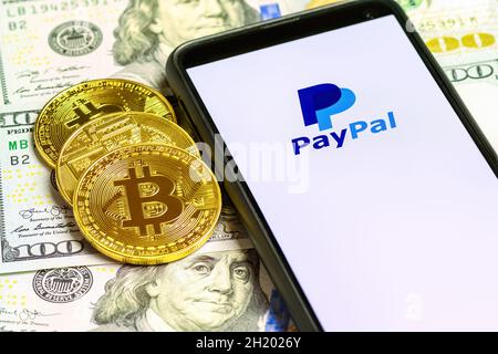 MOSCOU, RUSSIE - 14 OCTOBRE 2021 : logo PayPal sur l'écran du smartphone sur le fond des pièces de crypto-monnaie Bitcoin et du billet de banque en dollars américains Banque D'Images