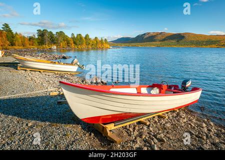 Bateaux en bois blanc sur la rive du lac avec des montagnes au loin.Beau jour ensoleillé d'automne dans l'Arctique suédois éloigné.Lac Lulealven, Stora Banque D'Images