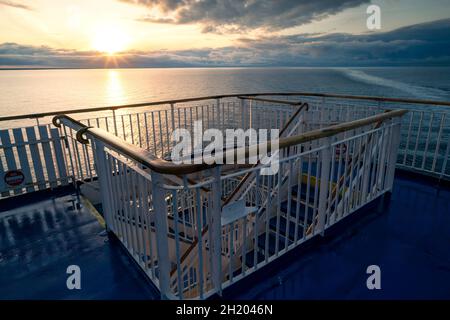 Lever de soleil épique sur la mer vu depuis le pont d'un navire en forme de cruse en direction de la Suède.Garde-corps et escalier en bois pour abaisser le pont à l'avant.Sunstar et Banque D'Images