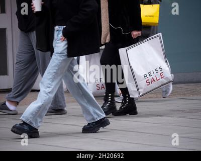 Riche pauvre Divide inégalité, Oxford Street London shopper holding a Reiss sale bag Reiss est une marque de mode aBritish et une chaîne de magasins de détail Banque D'Images