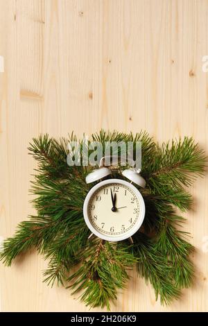 Concept de célébration du nouvel an.Réveil dans les branches d'un arbre de Noël sur fond de bois.Vue de dessus de la pose à plat Banque D'Images