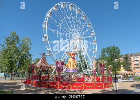 VELIKIYE LUKI, RUSSIE - 04 JUILLET 2021 : carrousel et grande roue dans le parc d'attractions de la ville pour enfants, le matin ensoleillé de juillet Banque D'Images