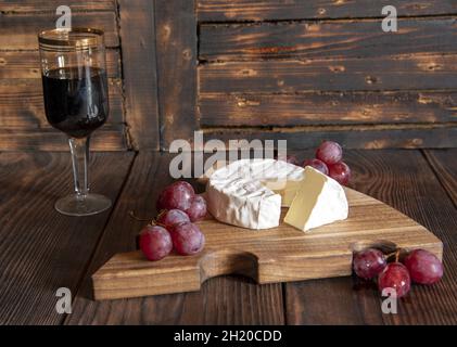 Fromage avec moule blanc et raisins sur une planche à découper en bois.La nourriture. Banque D'Images