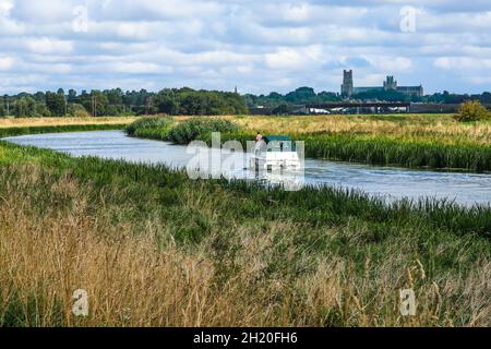 Un bateau de croisière à moteur se dirigeant en aval vers Ely avec une vue impressionnante de la cathédrale d'Ely, connue localement sous le nom de « la hanche des Fens » Banque D'Images