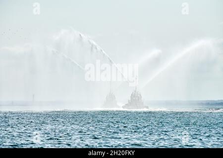 Remorqueurs flottants vaporisant des jets d'eau, faisant la démonstration de canons à eau pour lutter contre les incendies.Bateaux d'incendie pulvérisant de la mousse avec des tuyaux d'incendie.Navire-support offshore Banque D'Images