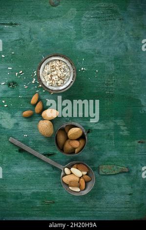 Amandes, décortiquées et non décortiquées, sur une cuillère et dans un bol, surface en bois rustique avec amandes effilées Banque D'Images