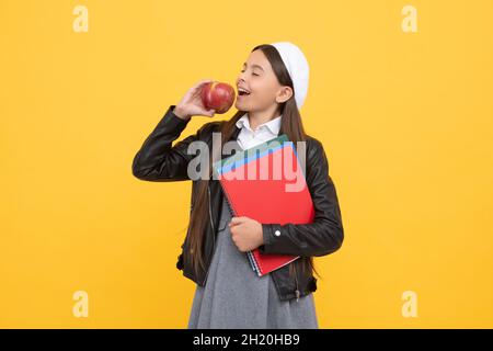 Heureux enfant d'âge scolaire profiter de manger savoureux bio vitamine pomme jaune fond, nourriture saine Banque D'Images