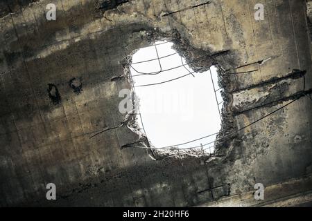 Ancien toit de maison endommagé abandonné avec trou dans le plafond donnant sur ciel nuageux.Mur de béton écroulé avec trou dans un bâtiment industriel abandonné, Banque D'Images