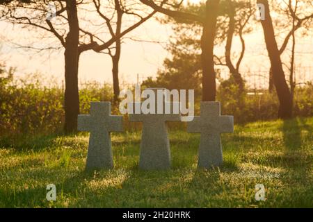 Trois pierres catholiques croissent sur de l'herbe verte au coucher du soleil dans le cimetière militaire allemand en Europe.Mémorial des soldats morts de la Seconde Guerre mondiale à Baltiysk, K Banque D'Images