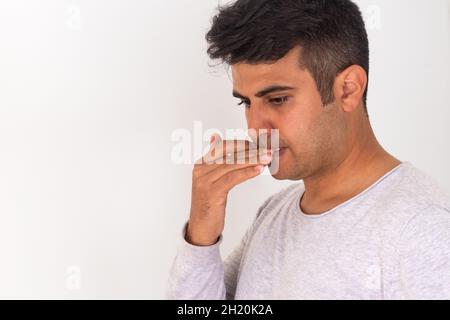 Homme stressé mordant les ongles de doigt sur un arrière-plan isolé. Banque D'Images