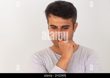 Homme stressé mordant les ongles de doigt sur un arrière-plan isolé. Banque D'Images