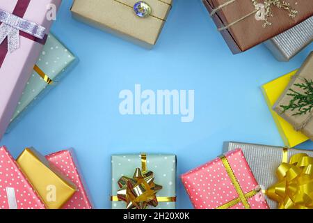 Vue du dessus des boîtes emballées dans des cadeaux.Cadre de Noël avec emplacement pour le texte.Cadeaux de différentes tailles enveloppés dans du papier cadeau décoré d'un ruban sur un fond bleu Banque D'Images