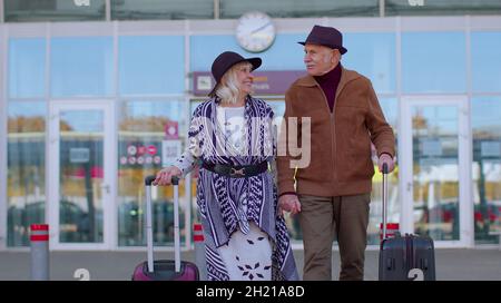 Grand-père de famille à la retraite élégant marchant avec des valises à bagages depuis le hall de l'aéroport Banque D'Images