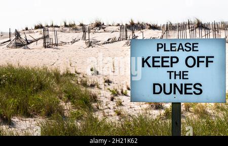 Gardez le panneau des dunes devant les dunes de sable avec des clôtures cassées sur le chemin du phare de Fire Island. Banque D'Images